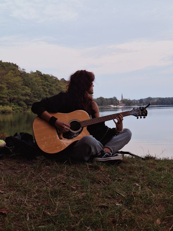 photographie d'un jeune homme au bord d'un lac avec une guitare seche